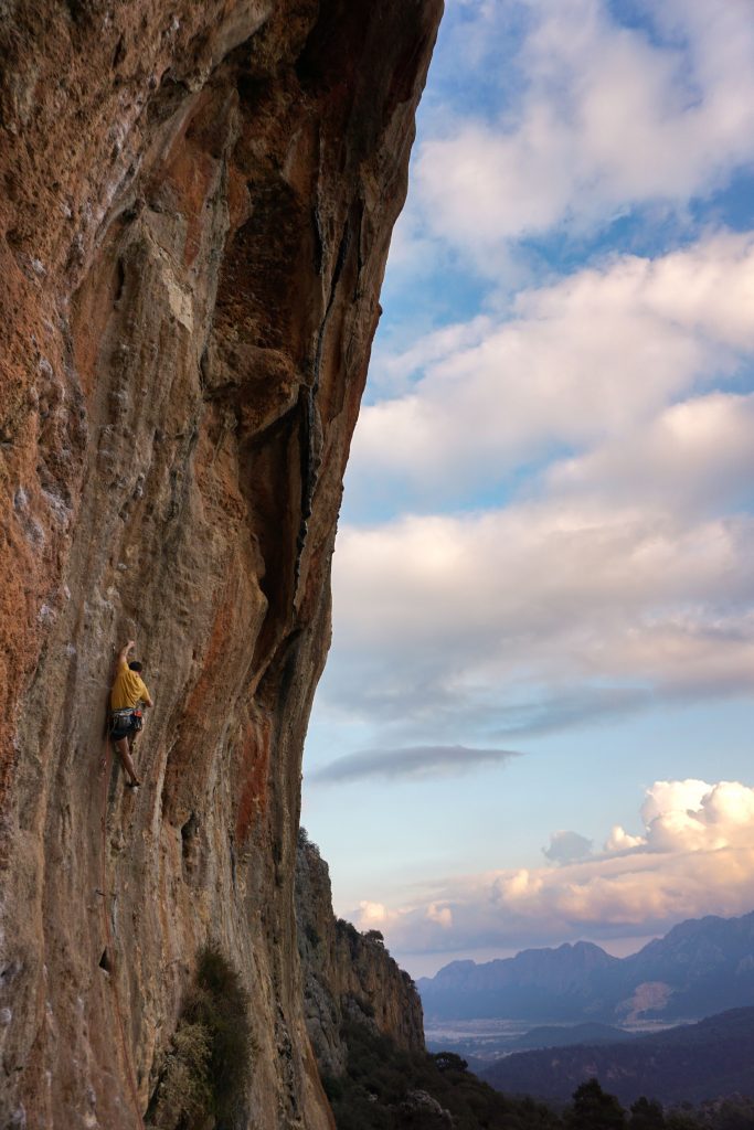 Man climbing a steep route on orange rocks of Geyikbayiri